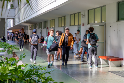 Professor talking to student, walking through Dooley Memorial Building.